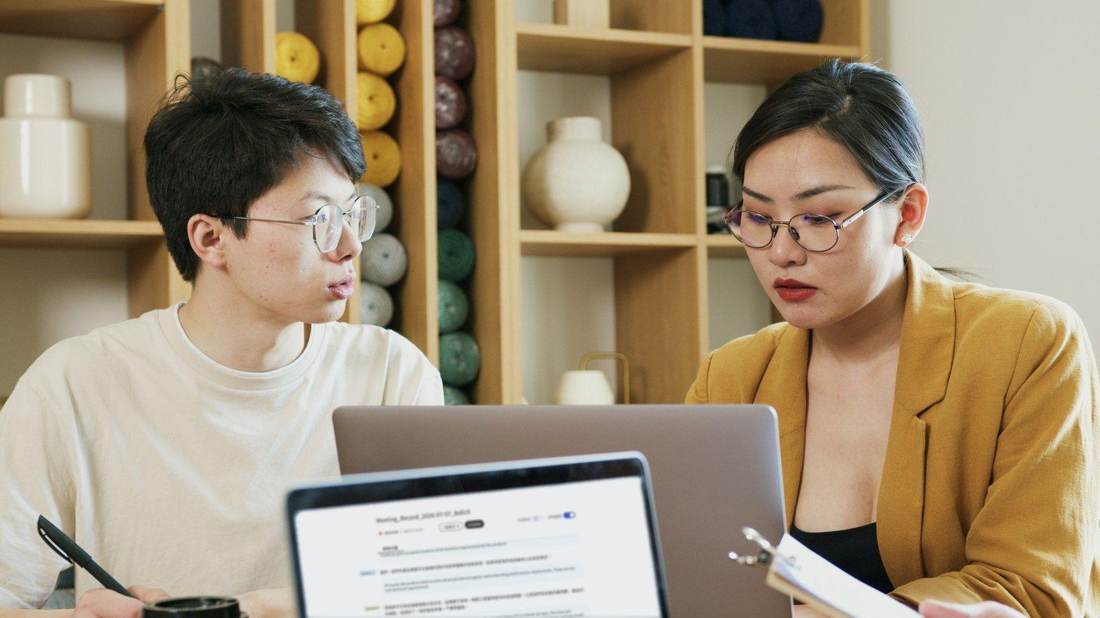 Consultant interviewing a company contact, with the Meeting Ink live transcript shown on a laptop